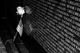 Horizontal A Rose and American Flag Leans Against the Vietnam Wall black and white Photos